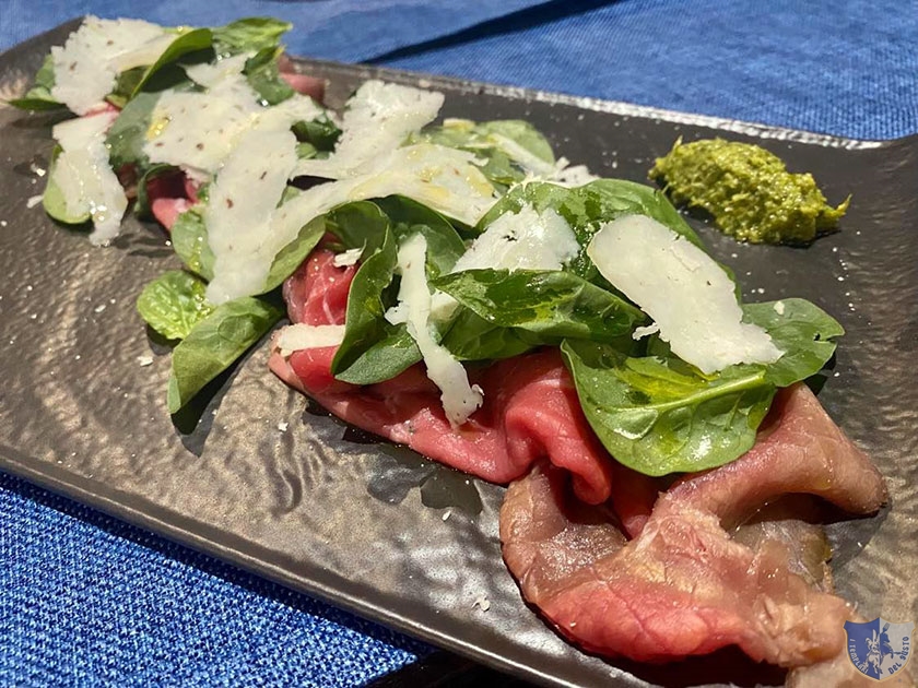 Carpaccio di carne salada con foglie di spinaci e scaglie di parmigiano