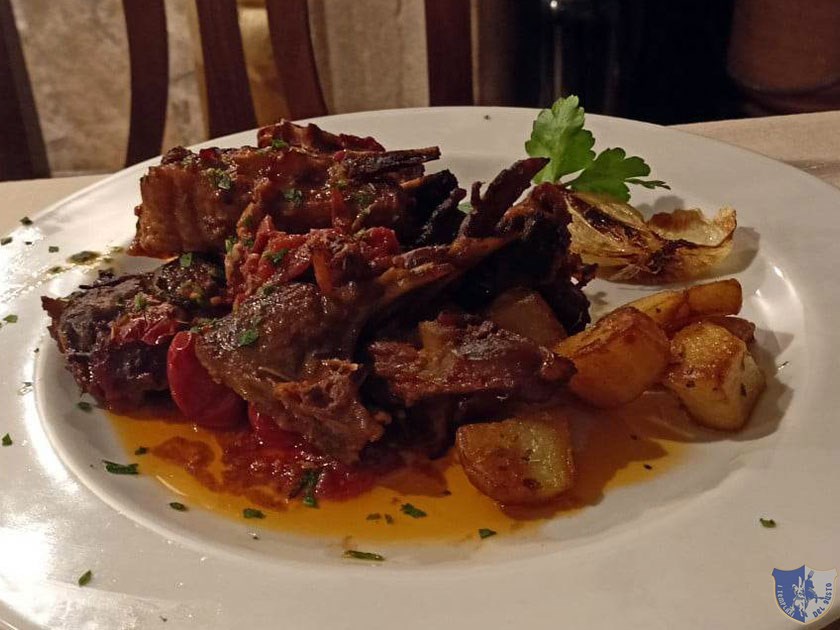 Agnello cotto nel forno a legna con salsa di pomodoro e patate