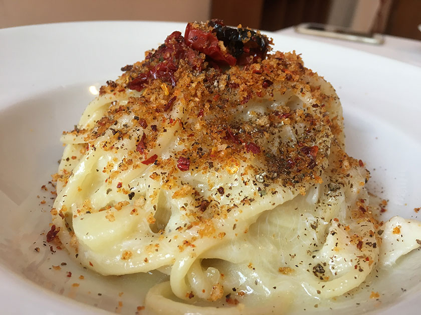 Spaghetti con baccalà, crema di patate, pan grattato aromatizzato con i peperoni cruschi, polvere di capperi e pomodorini infornati